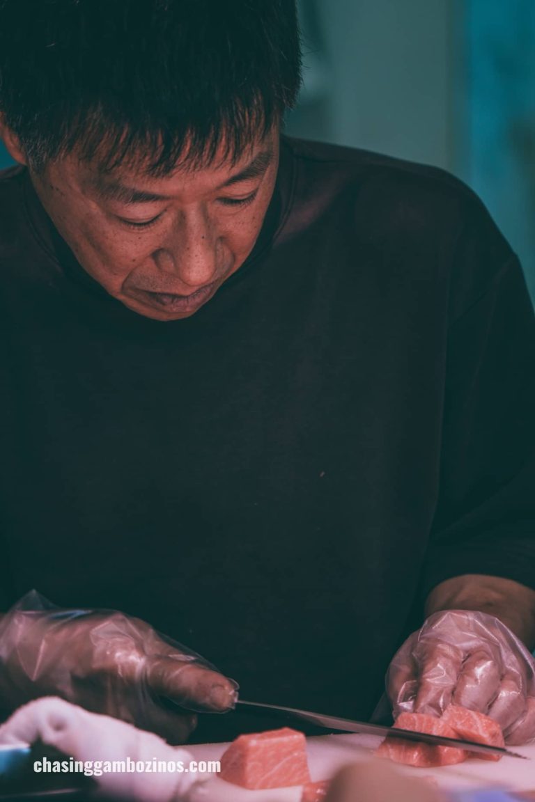 Sushiman cutting salmon in must visit Tokyo market.