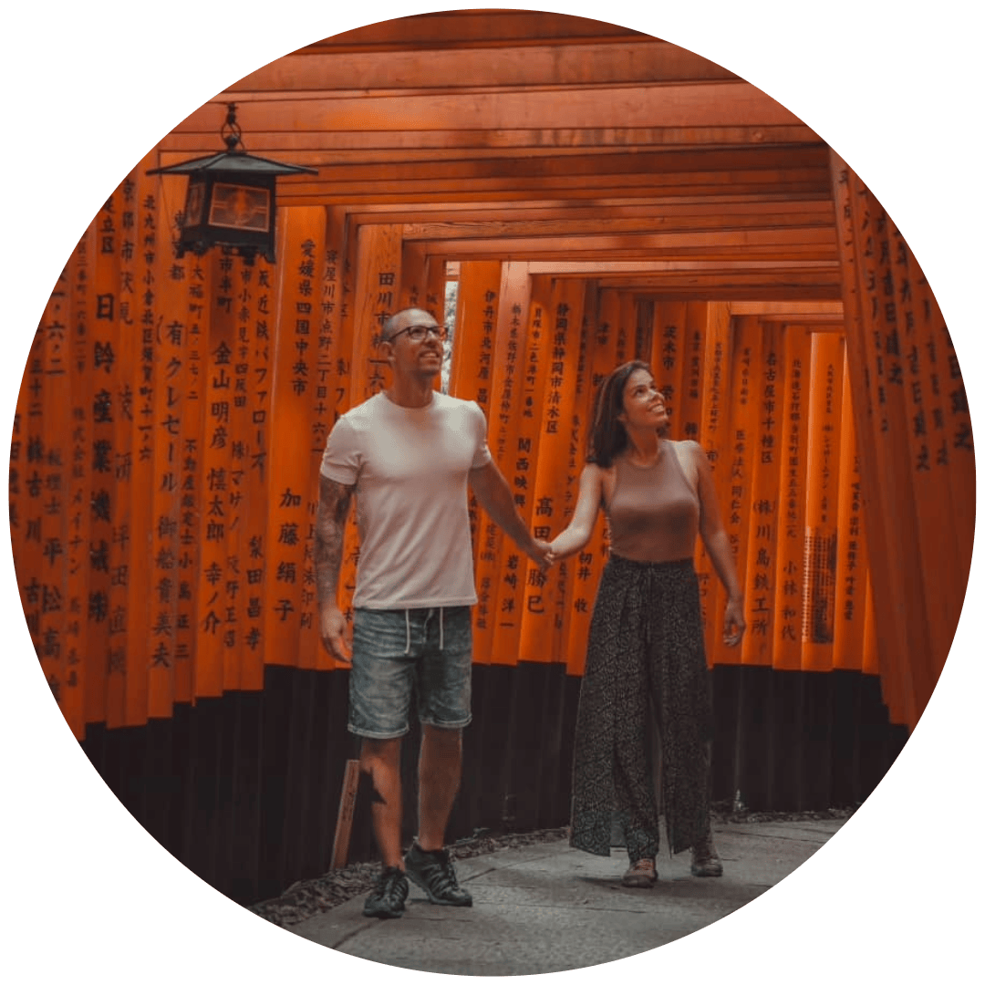 Casal a caminhar sob os portões torii vermelhos de Fushimi Inari, em Quioto, Japão.