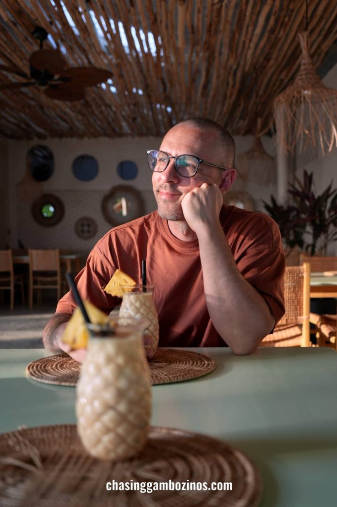 Homem a desfrutar de um cocktail num beach club em Koh Mak, Tailândia.
