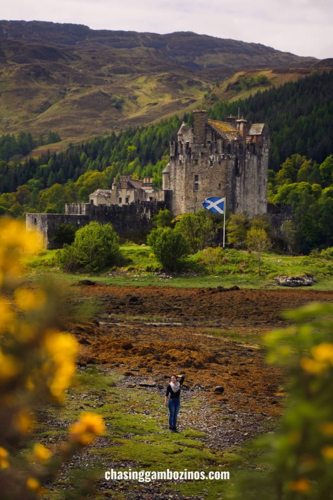 Woman walking by Eilean Donan Castle, a highlight of any Edinburgh to Isle of Skye tour.