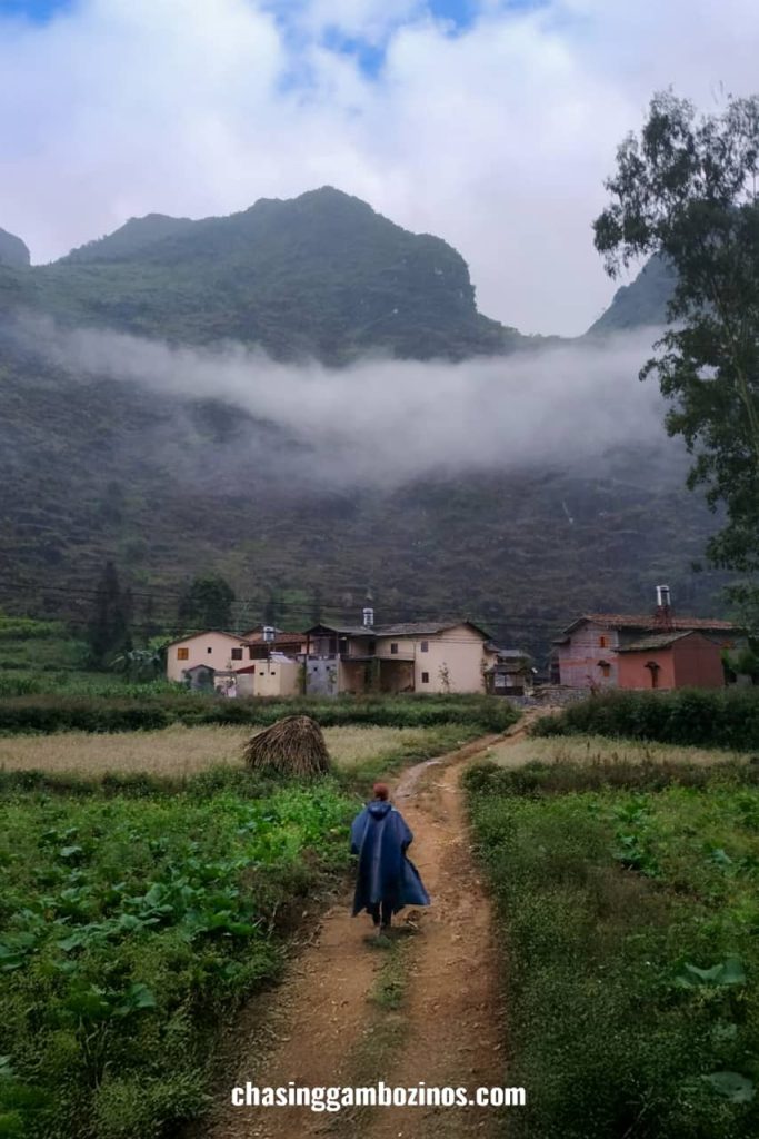 Woman walking towards a village in Meo Vac, one of the night stops on a Ha Giang loop itinerary.