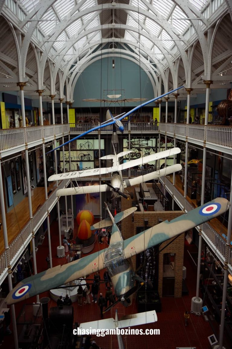 Pátio do National Museum of Scotland, com aviões suspensos no teto, uma visita a fazer em Edimburgo.