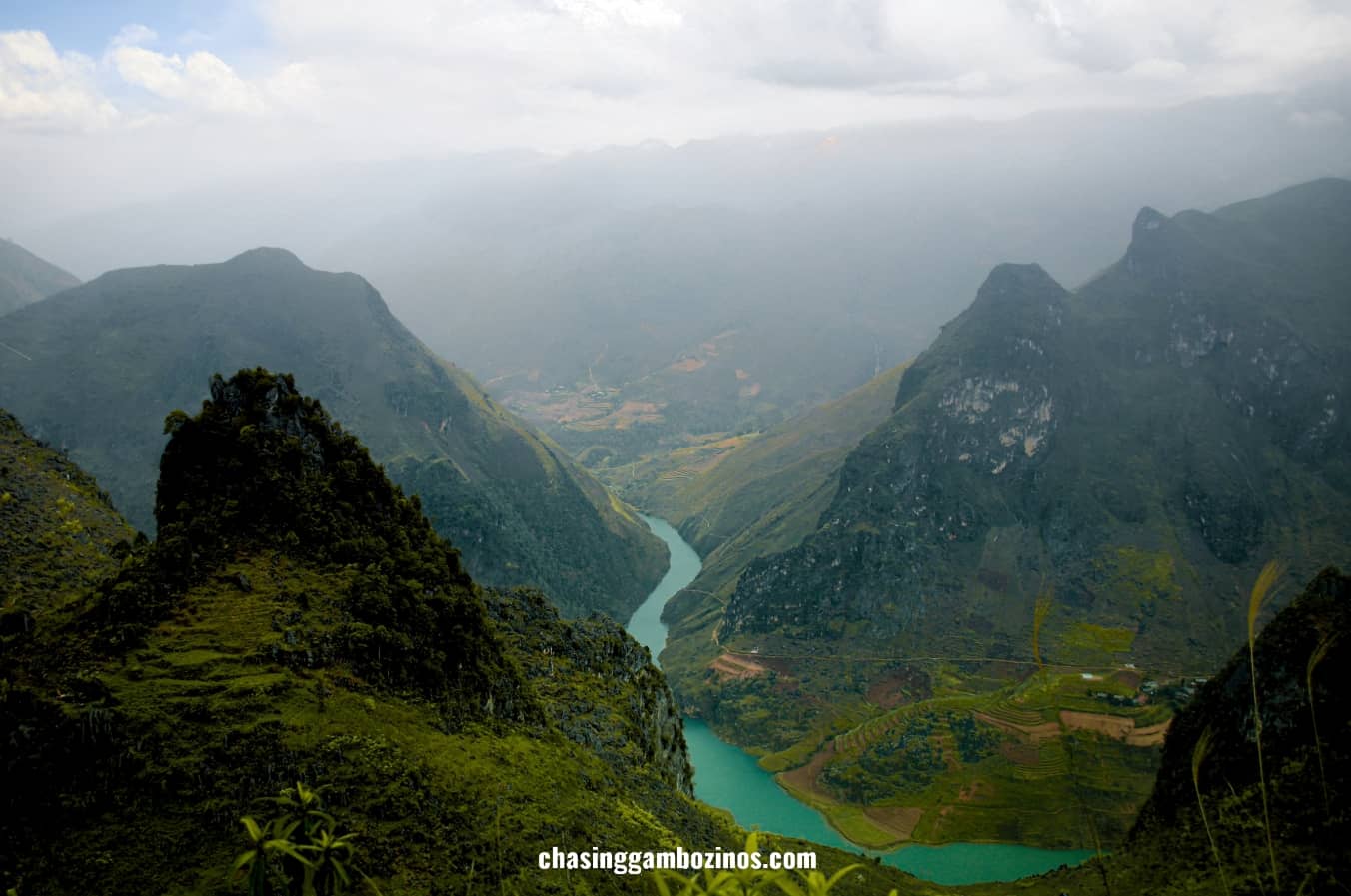Nho Que River emerald tone popping from between two mountains on a misty day, a place no Ha Giang travel blog can go without mentioning.
