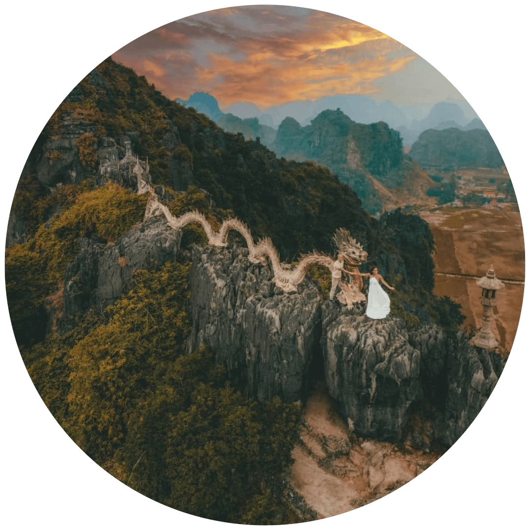 Casal de pé junto a uma estátua de dragão no topo das Grutas de Mua em Ninh Binh, Vietname.